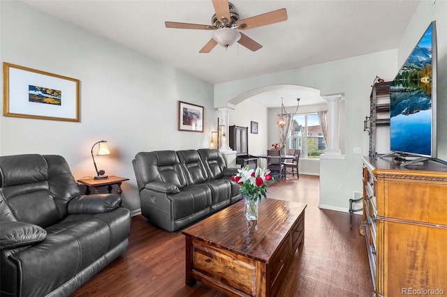living area featuring dark wood finished floors, arched walkways, a ceiling fan, and ornate columns