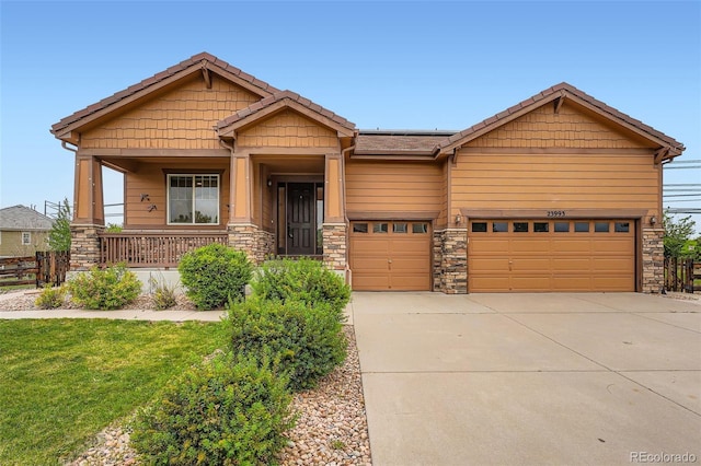 23993 E Briarwood Dr, Aurora, CO 80016 - craftsman house featuring concrete driveway, stone siding, covered porch, and a garage