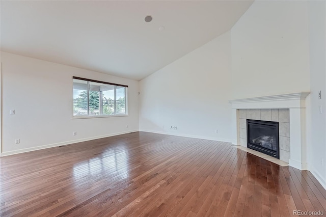 23993 E Briarwood Dr, Aurora, CO 80016 - unfurnished living room with hardwood / wood-style flooring, a tile fireplace, and high vaulted ceiling