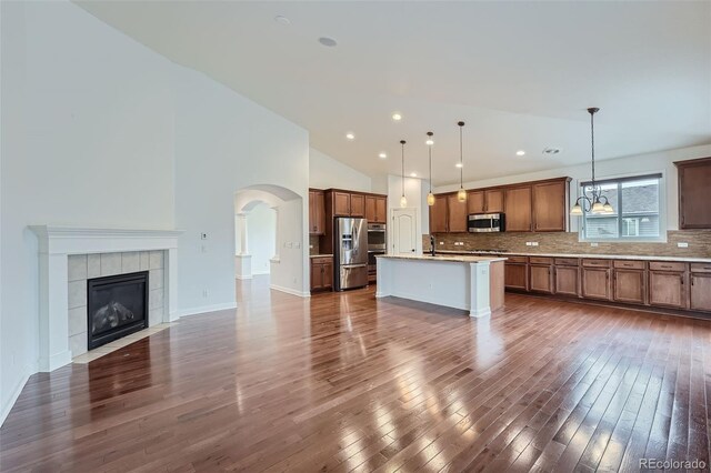 23993 E Briarwood Dr, Aurora, CO 80016 - kitchen with stainless steel appliances, open floor plan, decorative backsplash, dark wood finished floors, and arched walkways