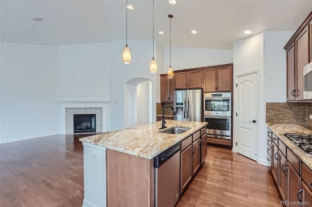 23993 E Briarwood Dr, Aurora, CO 80016 - kitchen with appliances with stainless steel finishes, arched walkways, decorative backsplash, light stone countertops, and lofted ceiling