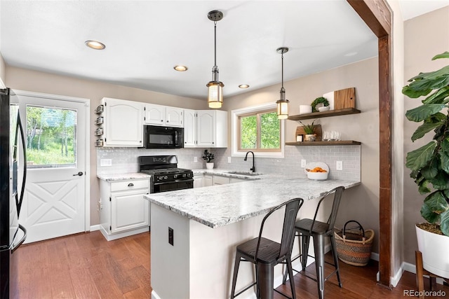 kitchen featuring sink, white cabinets, black appliances, and kitchen peninsula