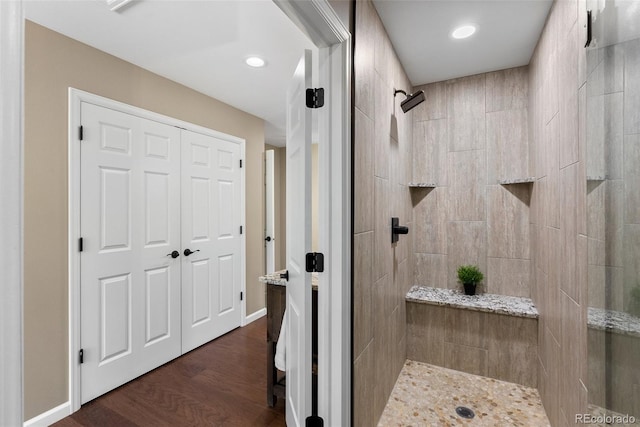 bathroom featuring wood-type flooring and a tile shower