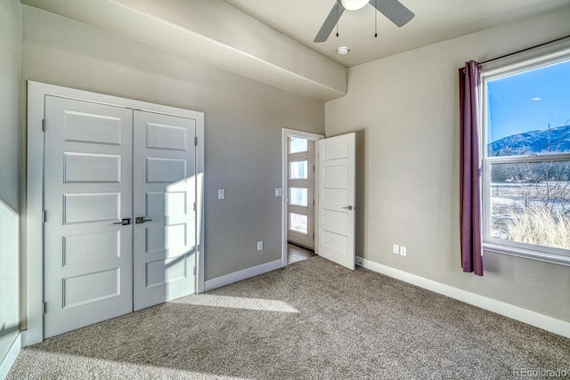 foyer entrance featuring ceiling fan and carpet