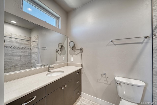 bathroom with toilet, vanity, and tiled shower