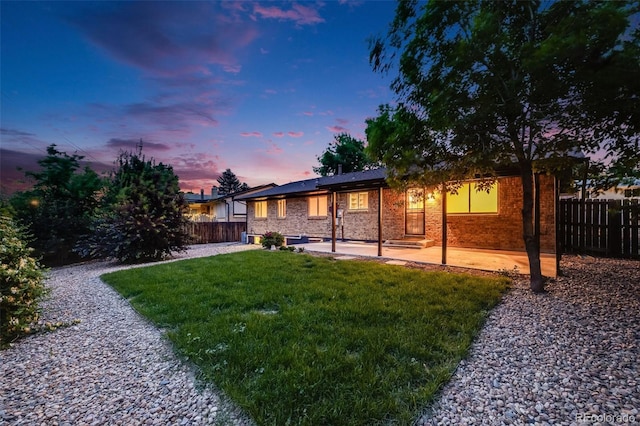 7382 E Bates Dr, Denver, CO 80231 - back of property at dusk with a patio area, a fenced backyard, and brick siding