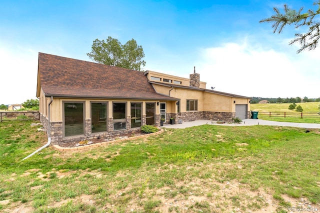 back of property with a garage and a lawn