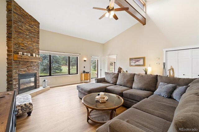 living room with light hardwood / wood-style flooring, beam ceiling, a fireplace, high vaulted ceiling, and ceiling fan