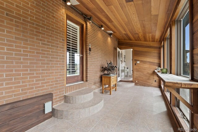 unfurnished sunroom with rail lighting and wood ceiling