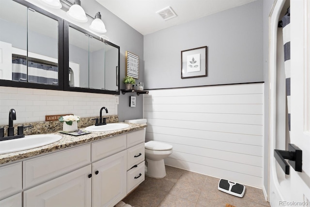 bathroom featuring tile patterned flooring, toilet, vanity, and tasteful backsplash