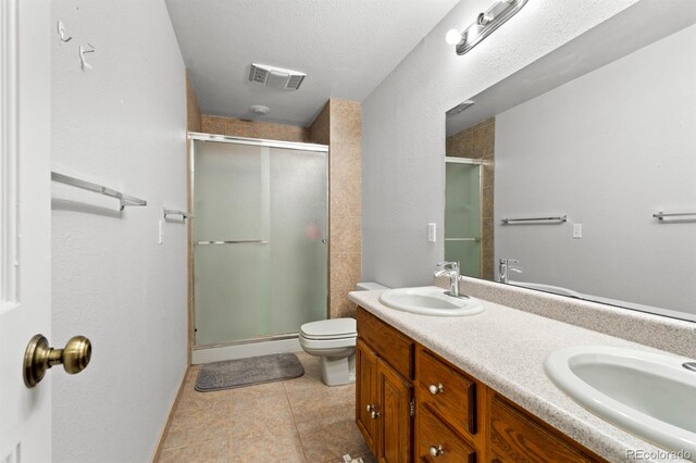 bathroom with toilet, tile patterned flooring, vanity, walk in shower, and a textured ceiling