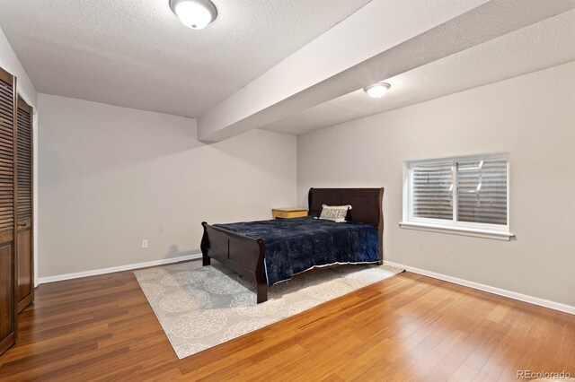 bedroom featuring a textured ceiling, beam ceiling, and hardwood / wood-style floors