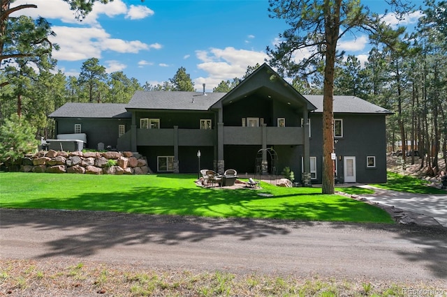 rear view of property with a yard and a balcony