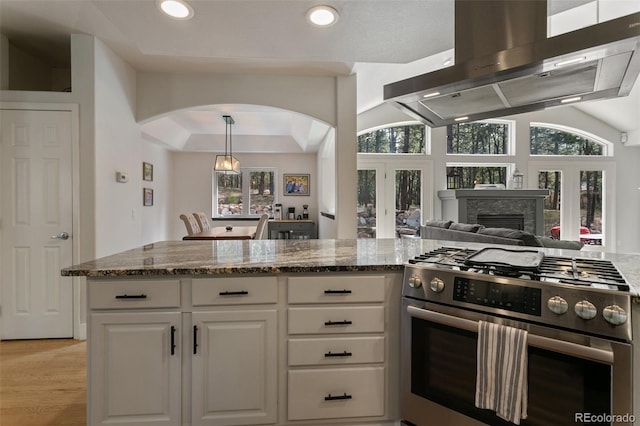 kitchen featuring light hardwood / wood-style floors, a fireplace, gas stove, white cabinets, and range hood