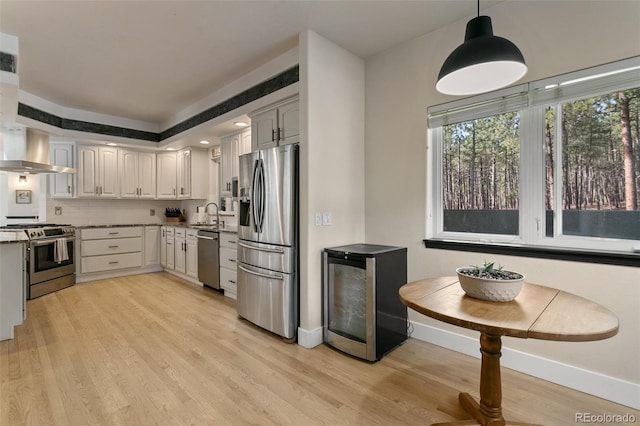 kitchen featuring light hardwood / wood-style flooring, stainless steel appliances, decorative light fixtures, ventilation hood, and tasteful backsplash