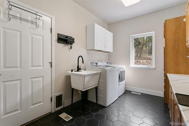 washroom with sink, independent washer and dryer, cabinets, and dark tile floors