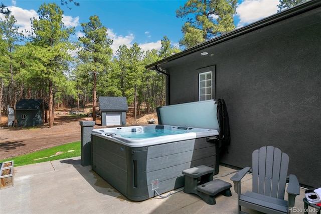 view of terrace with a hot tub and an outdoor structure