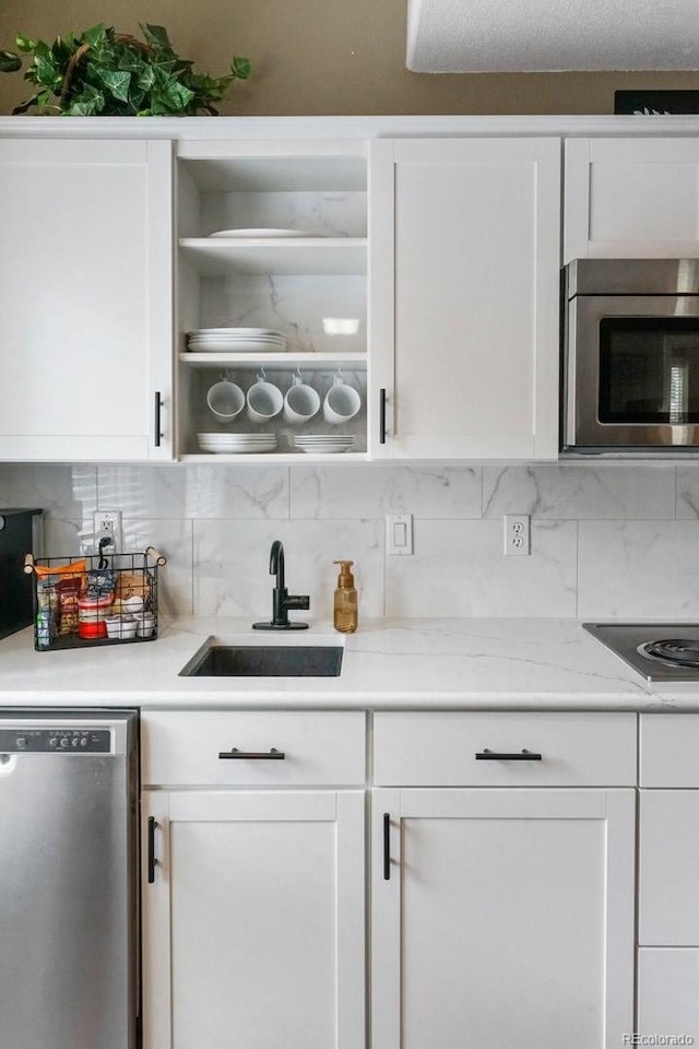 kitchen featuring a textured ceiling, backsplash, sink, white cabinetry, and appliances with stainless steel finishes