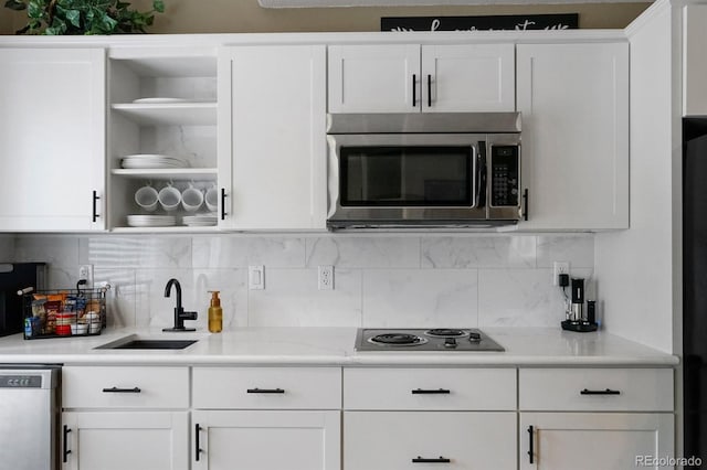 kitchen featuring appliances with stainless steel finishes, white cabinetry, sink, and backsplash