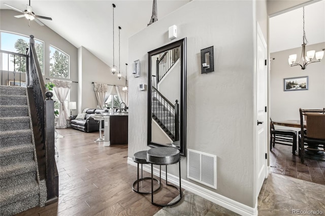 stairway featuring ceiling fan with notable chandelier, high vaulted ceiling, and hardwood / wood-style flooring