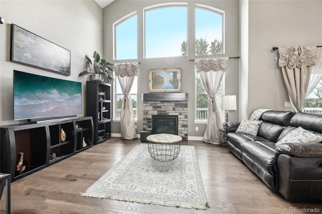 living room featuring a high ceiling, hardwood / wood-style floors, and a fireplace