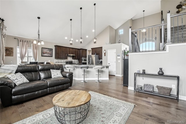 living room featuring dark hardwood / wood-style flooring, high vaulted ceiling, and an inviting chandelier