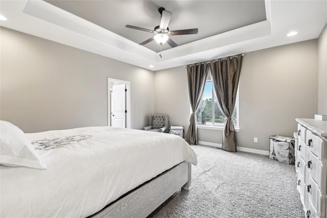 carpeted bedroom featuring ceiling fan and a raised ceiling