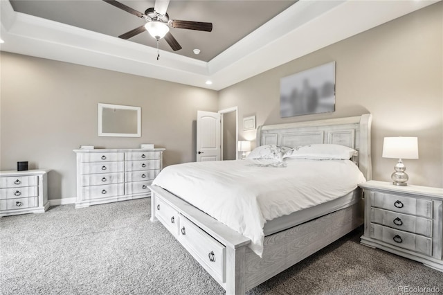 carpeted bedroom featuring a raised ceiling and ceiling fan