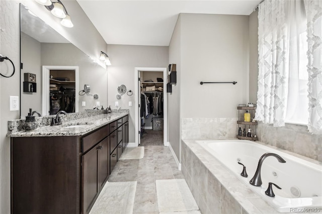 bathroom featuring plenty of natural light, vanity, and tiled tub