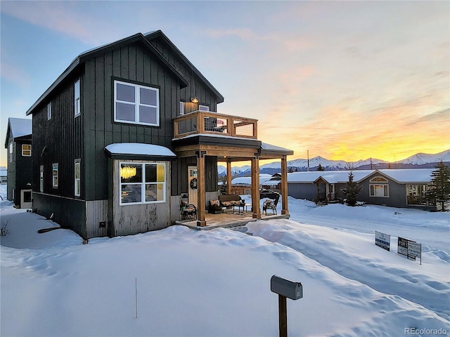 snow covered back of property with a balcony