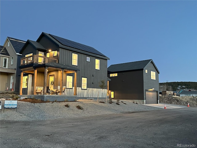 modern farmhouse featuring a balcony, a porch, and a garage