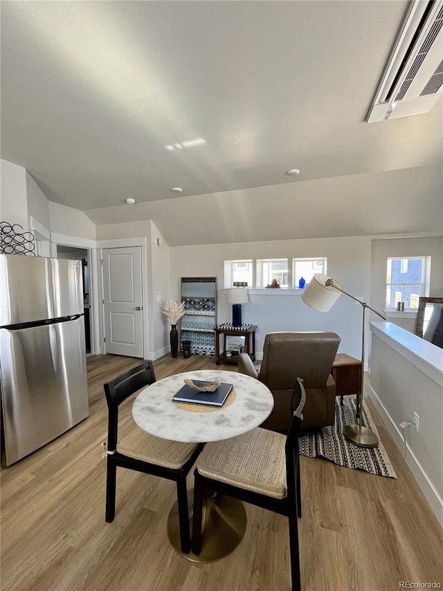 dining space with light hardwood / wood-style floors and lofted ceiling