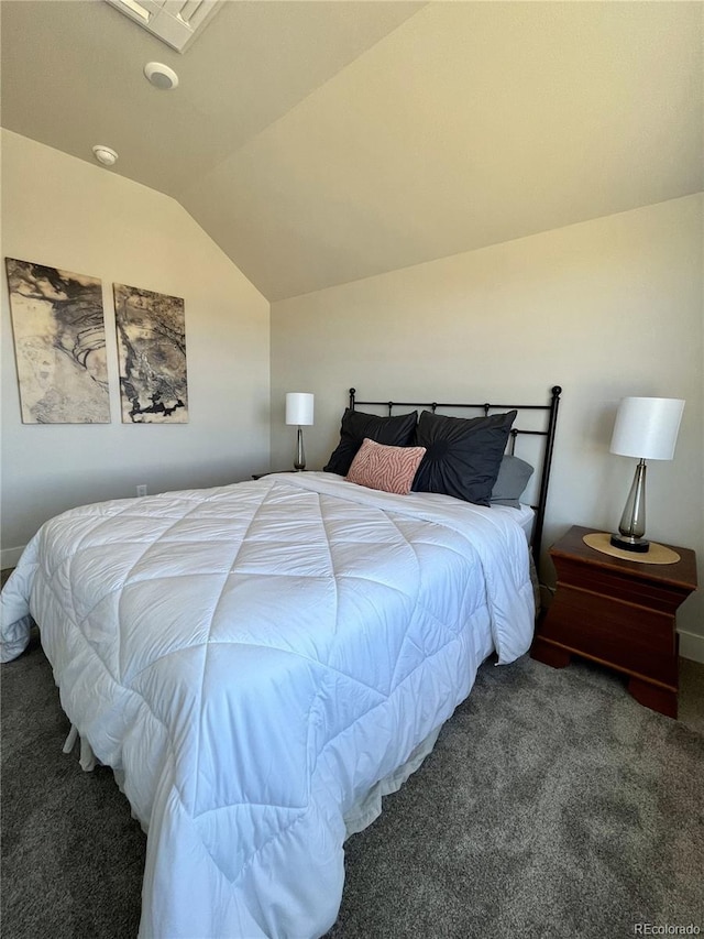 bedroom with dark colored carpet and lofted ceiling