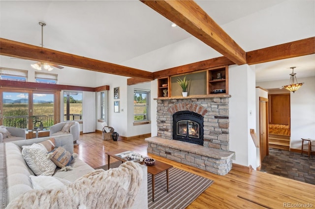 living room with light wood-type flooring, a fireplace, and beamed ceiling