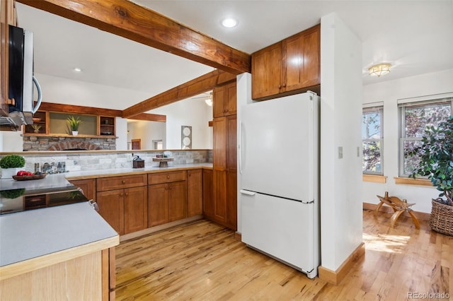 kitchen featuring beam ceiling, light hardwood / wood-style flooring, range, backsplash, and white fridge