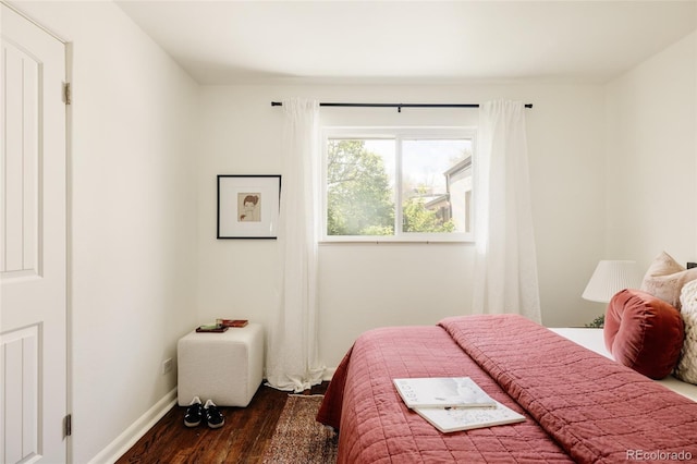 bedroom with dark wood-style flooring and baseboards