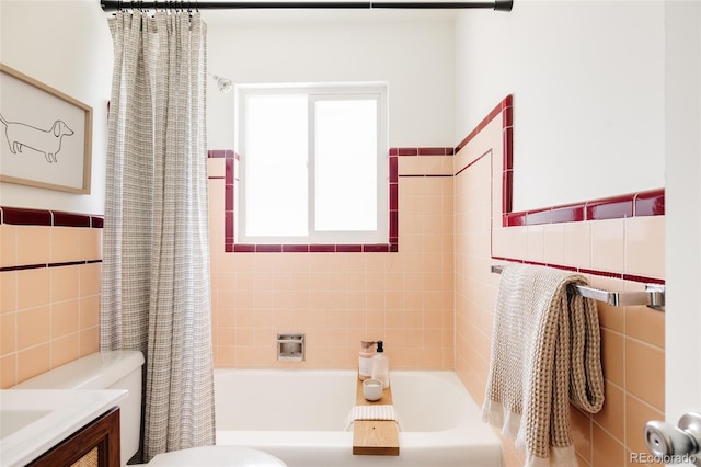 full bathroom with shower / bath combo, vanity, toilet, a wainscoted wall, and tile walls