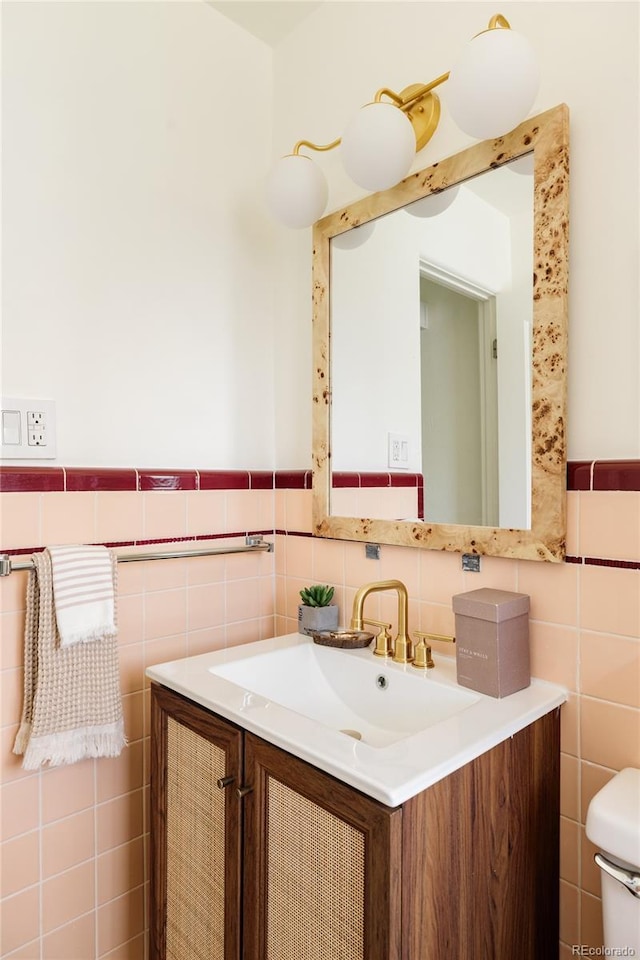 bathroom featuring vanity, a wainscoted wall, toilet, and tile walls