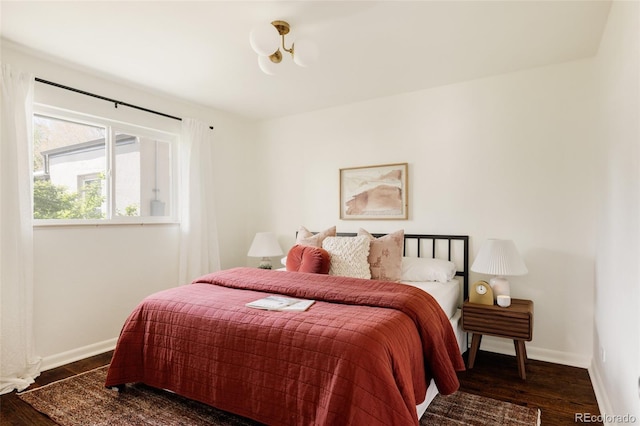 bedroom with baseboards, an inviting chandelier, and wood finished floors