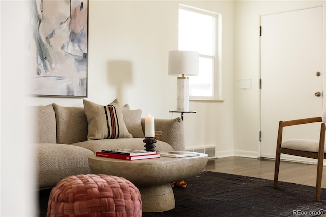 living area with baseboards, visible vents, and wood finished floors
