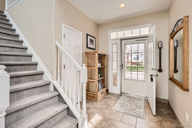 entrance foyer with recessed lighting, baseboards, stone finish flooring, and stairway