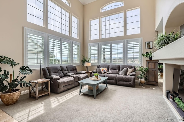 living area with a high ceiling, carpet, and a wealth of natural light