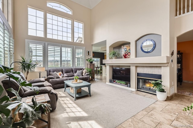 living room with baseboards, a high ceiling, a fireplace, and stone finish flooring