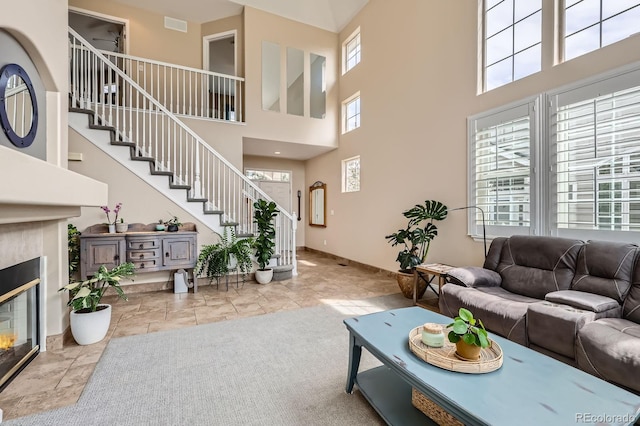living room featuring a healthy amount of sunlight, a high ceiling, a fireplace, and stairs