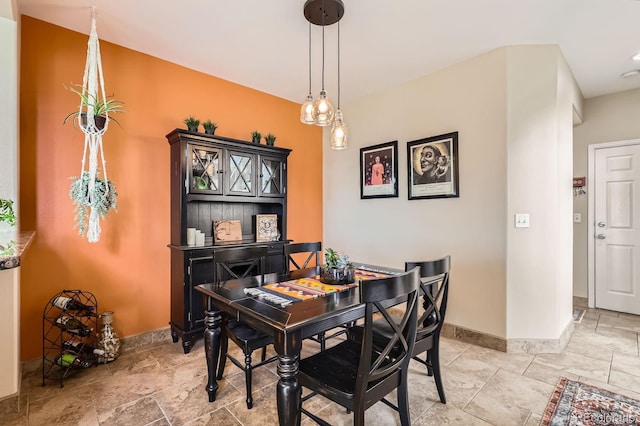 dining space featuring baseboards and stone tile flooring