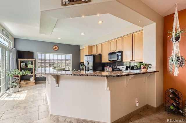 kitchen featuring a kitchen breakfast bar, black appliances, and a wealth of natural light
