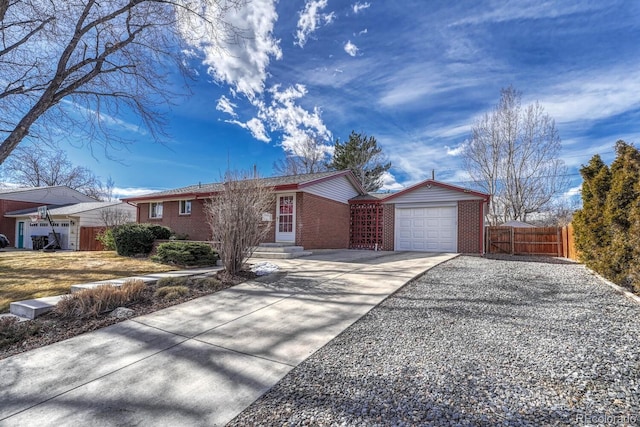 single story home featuring concrete driveway, brick siding, fence, and an attached garage