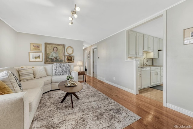 living area featuring crown molding, light wood finished floors, and baseboards