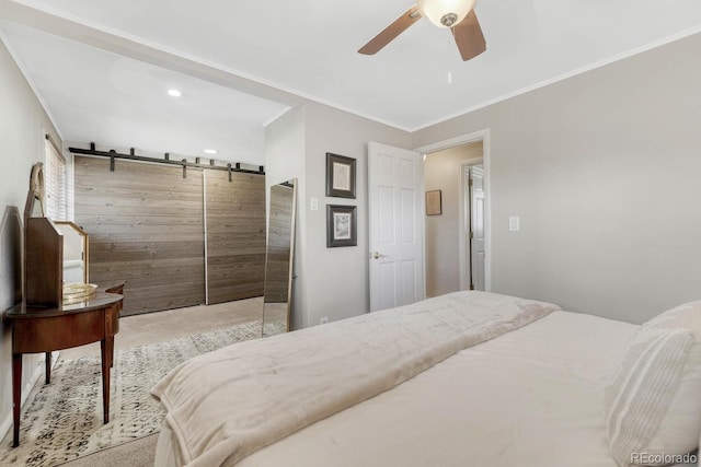 bedroom with ornamental molding, a barn door, a ceiling fan, and light colored carpet