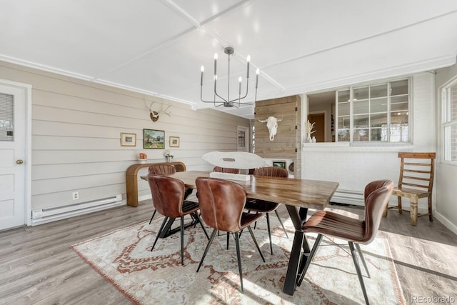 dining room featuring a baseboard radiator, light wood finished floors, and an inviting chandelier